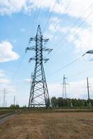 High voltage lines in a flat and green agricultural landscape on a sunny day with cirrus clouds in the blue sky. photo