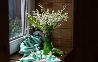 Bouquet white flowers Lily of the valley in glass Convallaria majalis, May bells, may-lily on a white table with space for text photo