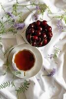 Fresh cherries bowl with leaves in water drops on stone background, top view photo