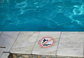 Do not jump into water sign on ground near swimming pool. Danger. photo