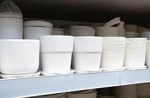 at row of white ceramic plant pot on the rack shelves. Different shapes and design. For sale. Fragile and handle with care. Concept of neat, peaceful, hobby, collection and gardening. Malaysia photo