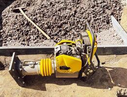 Small plate compactor, vibratory hammer, jumping jack machine, power tool at construction site photo
