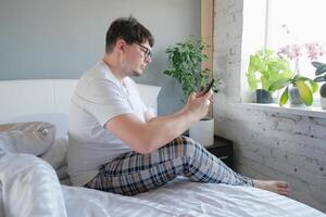 man waking up and having breakfast in bed and using smartphone photo