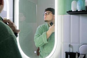 man Shaving Electric Razor in front of a Mirror photo