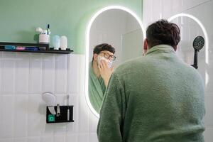 man Shaving with Electric Razor in front of a Mirror photo