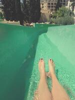 A person with painted toenails slides down a green water slide photo