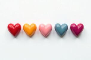 LGBTQ Pride month . Colorful rainbow heart-shaped objects arranged in a row on a white background photo