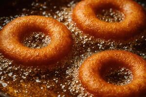 Close-up of golden brown donuts fried in heated oil with bubbles. the process of making donuts, Doughnut day. Fat Thursday photo