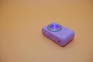 Close-Up of a Flashing Purple Toy Camera on Neutral Surface photo