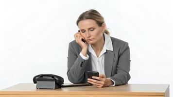 Woman Sitting at Desk Using Phone with Bored Expression photo