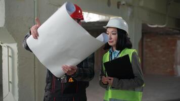 Two diverse Caucasian Japanese builders contractors man woman civil engineers architects workers in helmet uniform talking discussing blueprint paper planning building business project construction video