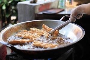 Man Hand Fried Chinese Deep Fried Dough Stick or Youtiao in Big Pan photo