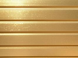 Shiny gold corrugated metal panels texture background with bright reflections and horizontal lines. Metallic siding surface backdrop design. photo