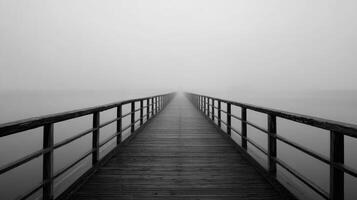 Fog covers the long wooden bridge leading into the unknown on a tranquil morning photo