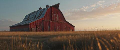 An old red barn sits in the middle of a field photo