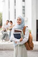 Diverse female student holding books and smiling on a university campus. photo