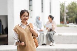Diverse female student smiling while holding notebooks on campus. photo