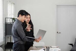 Business team collaborating on a project, discussing strategies with a laptop in a modern office. photo