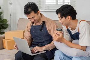Two young delivery professionals smiling while reviewing orders on a laptop in an inviting workspace photo