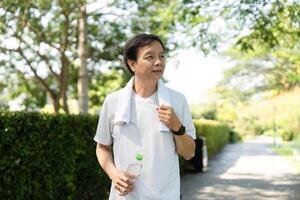 Wellness and Fitness. Man walking in the park with a towel and water bottle for hydration. photo