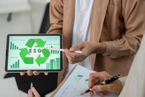 Visualizing ESG Principles. Professional displaying tablet with ESG graphics in business meeting. photo