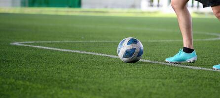 Soccer ball on green grass field with player wearing blue cleats preparing to kick during game, focusing on legs and ball in action on sports field photo