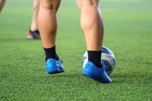 Soccer players in action during game on grass field focusing on their legs and ball, showing blue cleats and black socks in motion with blurred background photo