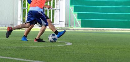 Two soccer players compete intensely for ball on green grass field, showcasing dynamic movement and athleticism during game. focus is on their legs and ball photo