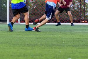 Soccer players in action on green grass field focusing on their legs and ball near goal net during intense game photo