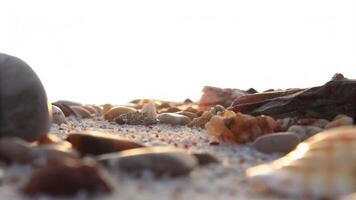 A close up view of pebbles and sand on a beach with bright sunlight in the background photo