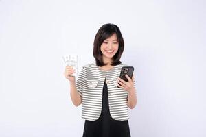 Southeast asian woman happily uses mobile phone to access internet application while holding cash in her hand showing excitement and success in digital finance photo