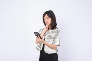 Southeast asian woman uses mobile phone with thoughtful expression while exploring internet application in bright minimalistic setting photo
