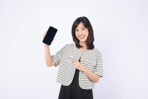 Southeast Asian woman smiling and pointing at mobile phone screen showing internet application in bright studio setting with casual striped jacket and black dress photo
