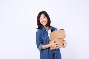 Southeast asian woman smiling happily while shopping online holds two cardboard boxes in her arms wearing casual denim clothes against plain white background photo