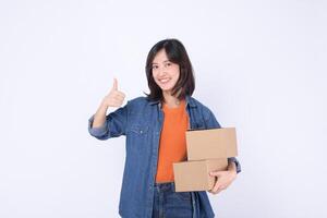 Southeast asian woman is happily shopping online holding two cardboard boxes and giving thumbs up gesture showing satisfaction and confidence in her purchase photo
