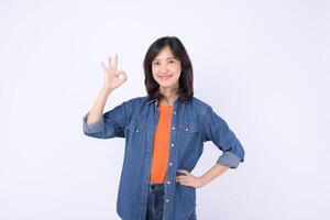 Southeast asian woman in casual denim shirt and orange top smiling confidently while making okay hand gesture on white background photo