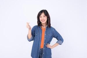Southeast Asian woman smiling and making heart gesture wearing denim jacket and orange shirt for advertising with confident and friendly expression photo