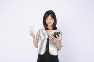 Southeast asian woman happily uses mobile phone application on internet while holding cash in her hand showing satisfaction and convenience in digital finance photo