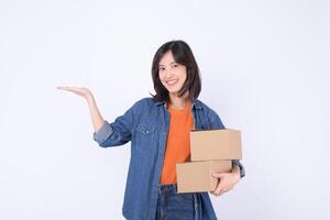 Southeast asian woman shopping online holds two cardboard boxes and smiles happily showing open hand gesture on white background photo