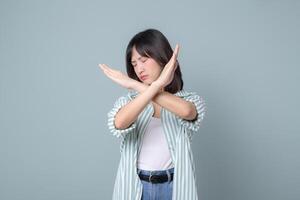 Southeast asian woman shows stop gesture with crossed arms expressing refusal or no in creative way for small business owner in retail or online store startup industry photo