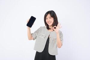 Southeast asian woman happily shows mobile phone with internet application on screen while making okay gesture expressing confidence and satisfaction photo