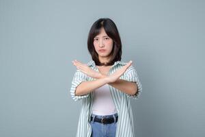Southeast asian woman showing stop gesture with crossed arms expressing refusal or disapproval in creative and confident way photo