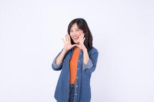 Cheerful southeast asian woman in casual denim outfit smiling and posing for advertising with hands near her face in bright studio setting photo