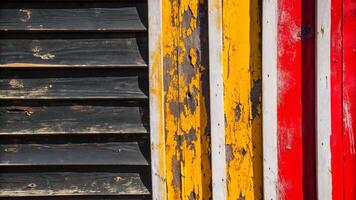Close up of weathered wooden planks painted in black, yellow, white, and red colors photo