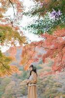 Southeast asian woman enjoys travel concept in autumn forest surrounded by colorful leaves creating peaceful and inspiring atmosphere for reflection and adventure photo