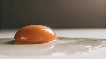 A single egg yolk resting on a white surface with a blurred background in studio shot photo