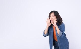 Southeast asian woman in denim jacket is shouting with hands near her mouth for advertising or calling out with energetic expression photo