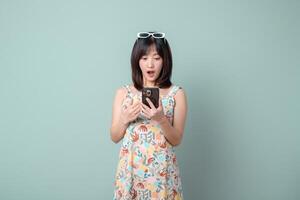 Southeast asian woman using mobile phone with surprised expression enjoying internet application on pastel background photo