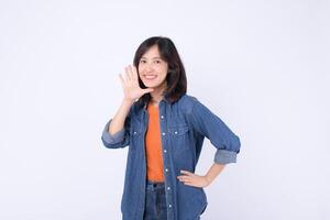 Cheerful southeast asian woman in denim jacket is advertising with friendly smile and raised hand showing five fingers in bright studio setting photo
