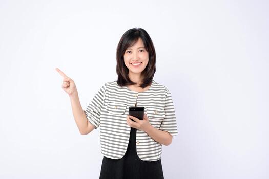 Southeast asian woman is happily using mobile phone while pointing to side, showing excitement about internet application on white background photo